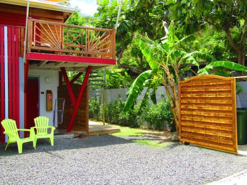 a patio with a deck and two chairs next to a house at Katalo Plage in Deshaies