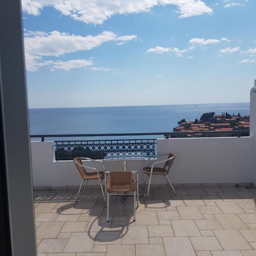 a table and chairs on a balcony with a view of the ocean at Vila Horizont in Sveti Stefan