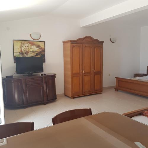a living room with a tv and a wooden cabinet at Vila Horizont in Sveti Stefan