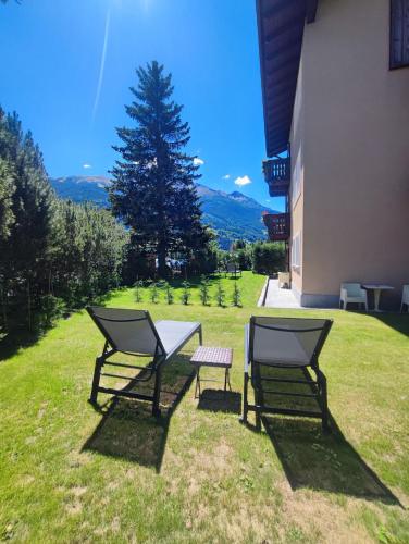 two chairs and a table in the grass next to a building at Alpi & Golf Hotel in Bormio