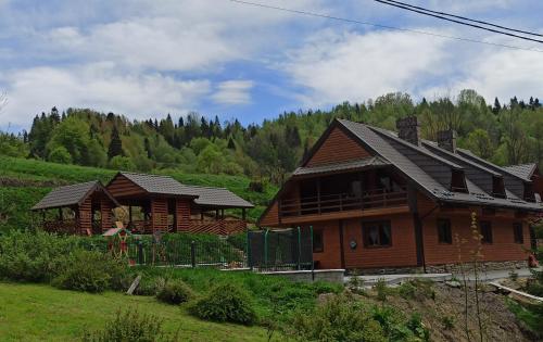 two wooden houses in a field with trees in the background at Сімейний Затишок апартаменти in Oryavchyk