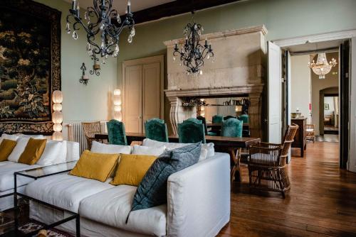 a living room with a white couch and a dining room at Hôtel Restaurant de Bouilhac in Montignac