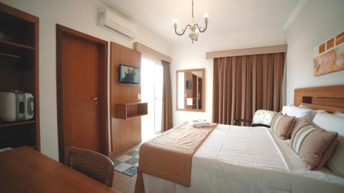 a hotel room with a large bed and a table at Hotel Água Viva - By UP Hotel in Cachoeira Paulista