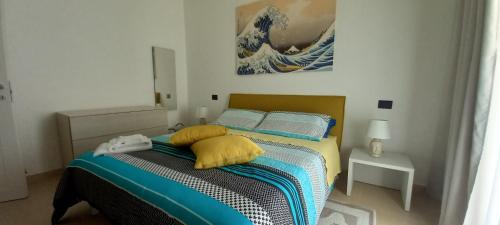een slaapkamer met een bed met gele en blauwe kussens bij Kalimera Guest House in Giardini Naxos