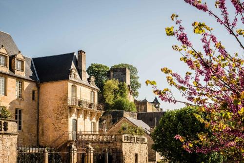 an old brick building with a castle in the background at Hôtel Restaurant de Bouilhac in Montignac