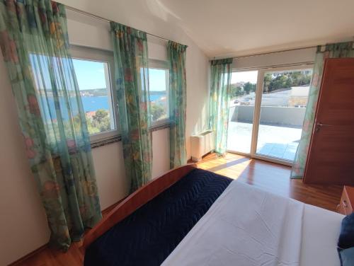 a bedroom with a bed and two large windows at Villa Sanja I in Trogir