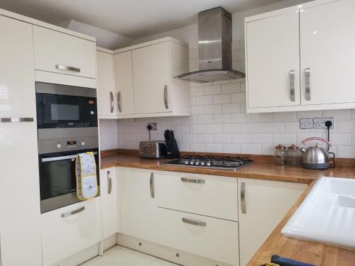 a kitchen with white cabinets and a stove top oven at Bee At Home in Cefn-coed-y-cymmer