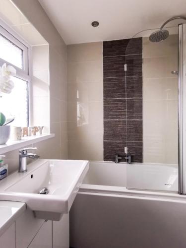a white bathroom with a tub and a sink at Bee At Home in Cefn-coed-y-cymmer