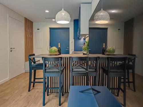 a kitchen with a table with chairs and blue walls at Comfy Rest apartamentai Kalno namuose in Juodkrantė