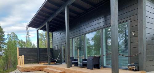 une maison avec des fenêtres en verre, une table et des chaises dans l'établissement Villa Paatari, Inari (Paadarjärvi), à Inari