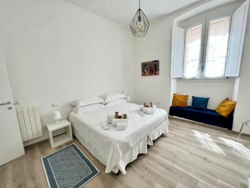 a white bedroom with a bed and a blue couch at La casa di Ale nel centro storico di Cagliari in Cagliari