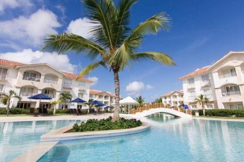 a palm tree in front of a hotel with a swimming pool at Fabulous Caracol Cadaques Caribe in Bayahibe