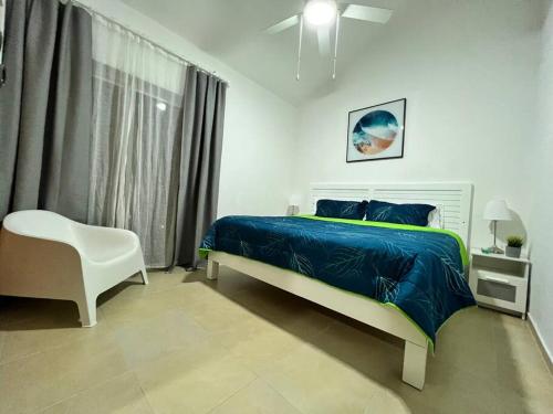 a bedroom with a bed and a white chair at Fabulous Caracol Cadaques Caribe in Bayahibe