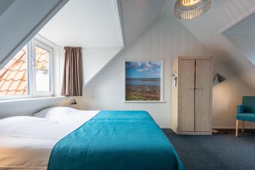 a bedroom with a large bed and a blue chair at Hotelletje de Veerman in Oost-Vlieland