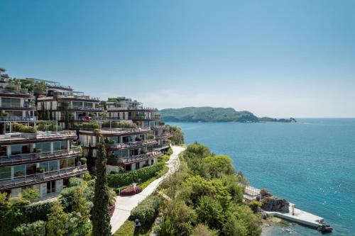 a row of houses on a hill next to the water at Dukley Hotel & Resort in Budva