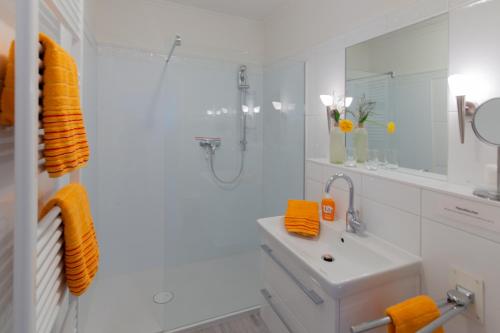 een witte badkamer met een wastafel en een douche bij Komfort Ferienwohnung Steiger in Timmendorfer Strand
