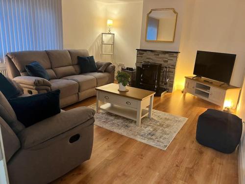 a living room with a couch and a tv at Whitehorse House in Donegal