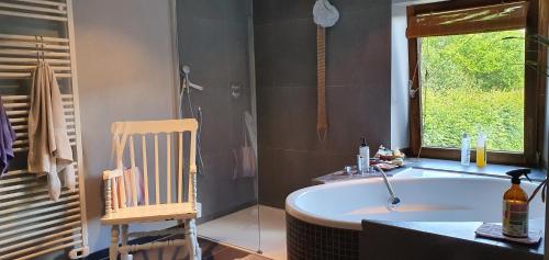uma casa de banho com uma banheira e uma cadeira. em Chambre d'Amandine em Gerpinnes
