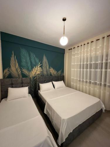 2 Betten in einem Zimmer mit einer Wand mit Pflanzen in der Unterkunft Dragoti Apartment 2 in Golem
