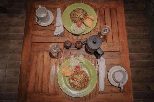 una mesa de madera con dos platos de comida. en Jepun Didulu Cottages, en Candidasa
