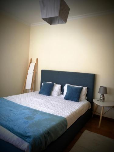a bedroom with a large bed with blue pillows at Casa Avó Rosa in Nazaré