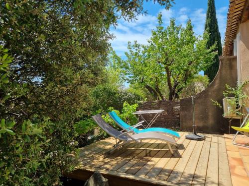 two chairs and a table on a wooden deck at Les Garrigues de la Vallée des Baux in Paradou