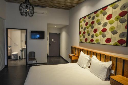 a bedroom with a bed and a painting on the wall at Cit'Hotel Le Relais du Boisniard in Chambretaud