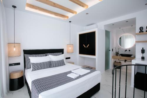a white bedroom with a bed and a mirror at Naxos Black Concept Maisonette in Naxos Chora