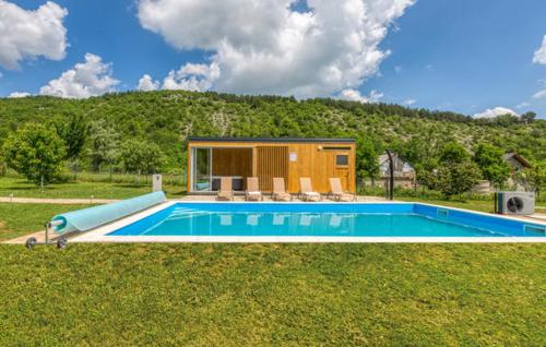 a small house with a swimming pool in the grass at Manuela in Gospić