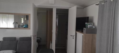 un salon avec un canapé et une télévision dans l'établissement Vacances a la campagne mobil home tout confort , chalet avec barbecue,, à Javron-Les-Chapelles