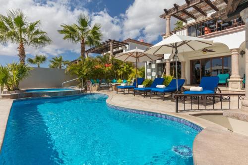 a pool with chairs and umbrellas next to a house at The Residences at Hacienda Encantada in Cabo San Lucas