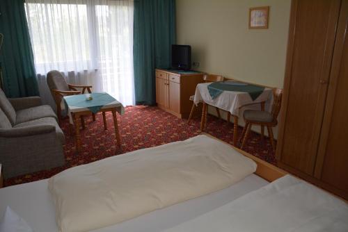 a hotel room with a bed and a table and chairs at Kurpension Gundula in Bad Füssing
