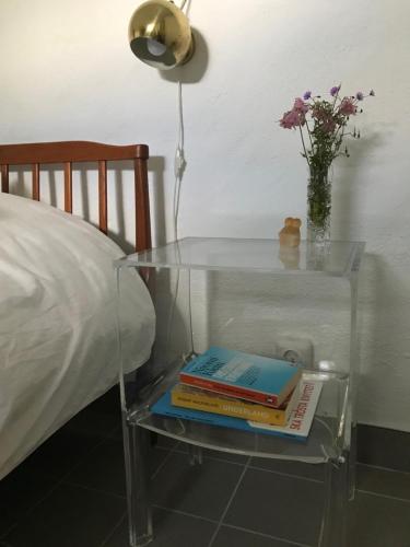 a glass table with books on it next to a bed at Doubleroom in basement w own bathroom in Rörum, Österlen in Simrishamn