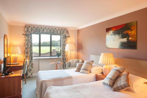 a hotel room with two beds and a window at Woodbury Park Hotel & Spa in Exeter
