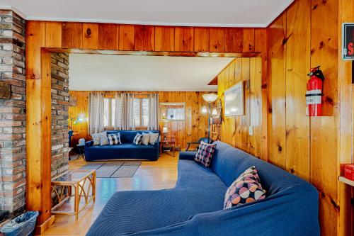 una sala de estar con muebles azules y paredes de madera. en Island Forest Retreat, en West Tisbury