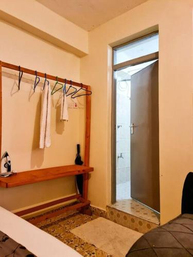 a bathroom with a shower and a glass door at Cozy Spacious Studio Apartment close to Town in Nanyuki