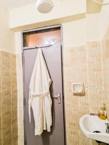 Łazienka z umywalką i ręcznikiem wiszącym na drzwiach w obiekcie Cozy Spacious Studio Apartment close to Town w mieście Nanyuki