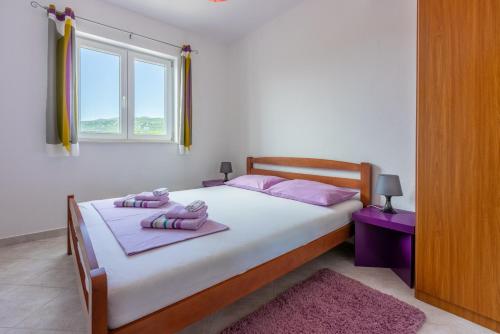 a bedroom with a bed with pink pillows and a window at Apartmani Jarić in Novi Vinodolski