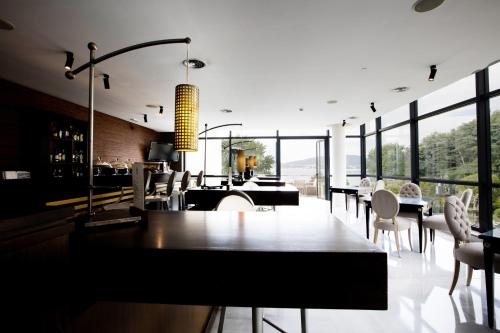 a restaurant with a table and chairs and windows at Pazo Los Escudos Hotel Spa & Resort in Vigo