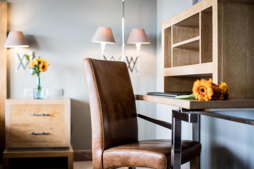 a desk with a chair and a table with flowers on it at Pazo Los Escudos Hotel Spa & Resort in Vigo