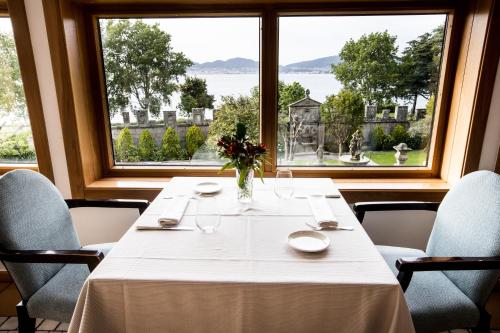 a dining room with a table and a large window at Pazo Los Escudos Hotel Spa & Resort in Vigo