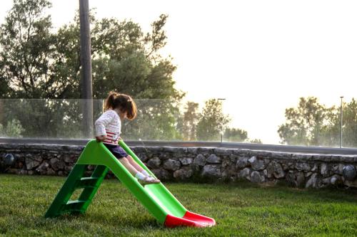 a little girl playing on a slide at a park at Liogerma Apartments in Tsoukaladhes