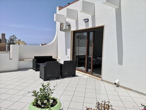 biały budynek z patio z czarnymi meblami w obiekcie B&b tra scirocco e tramontana w mieście Gallipoli