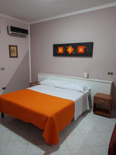 a bedroom with a bed with an orange blanket at Hotel De Rosa in Boscoreale