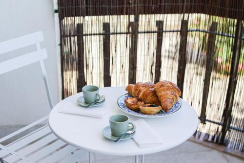 a table with a plate of croissants and cups of coffee at Charming TM Flat by the Ocean with a View in Cruz Quebrada