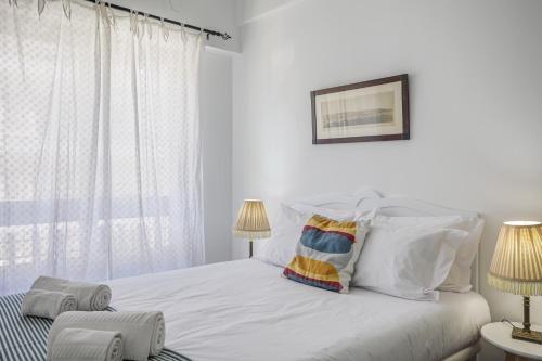 a white bedroom with a bed with white pillows at Charming TM Flat by the Ocean with a View in Cruz Quebrada