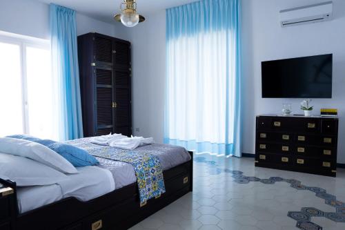 a bedroom with a bed with blue walls and a television at Villa Paradise (Amalfi Coast - Luxury Home - Beach) in Vietri sul Mare