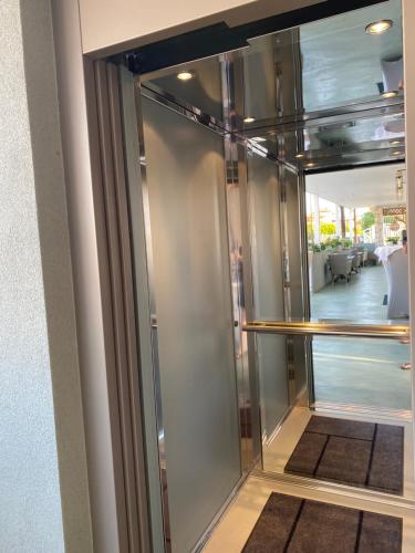a glass elevator in a room with a hallway at T H E BERLIN Studios and Suites in Nea Vrasna