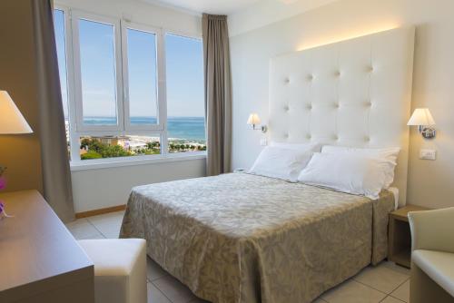 a hotel room with a bed and a large window at Hotel Cristallo in Riccione