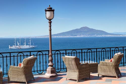 a group of chairs and a street light next to the ocean at Grand Hotel Royal in Sorrento